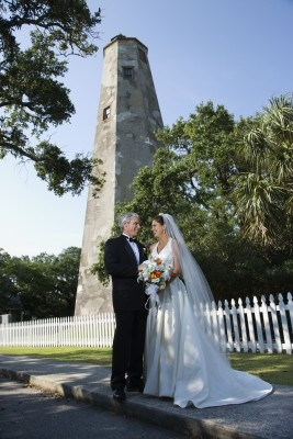 A handsome wedding couple takes photos in front of the Bald Head Island Lighthouse.